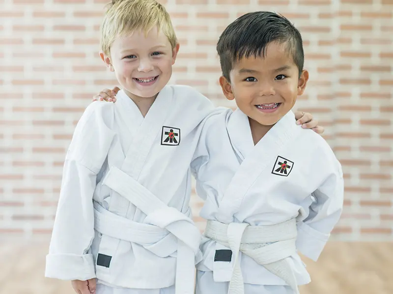 wo smiling young boys wearing white uniforms during a Little Dragons class.